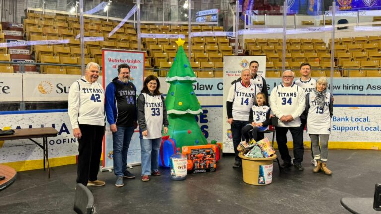 Group of people at the KW Titans game standing by a Christmas tree with toys.