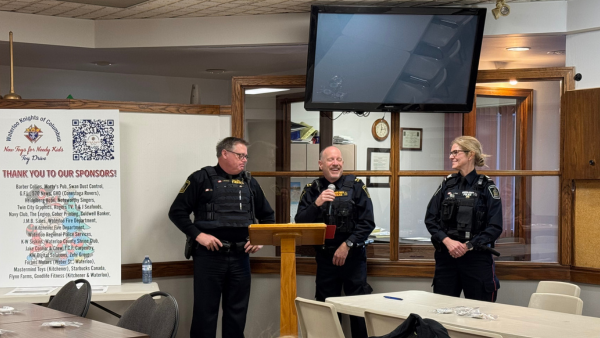 Three police offices - two men and a women, speaking in front of a room with a microphone