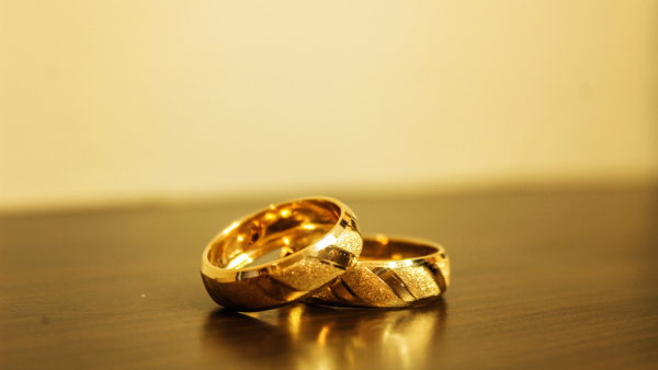 two gold wedding rings laying together on a wooden table