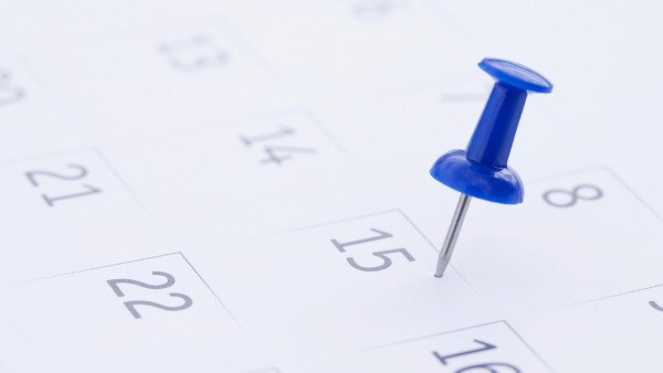 close of up a calendar page with a blue push pin sticking out of it.